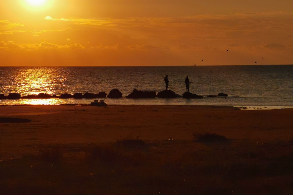 Due pescatori nella cornice di un tramonto sulla spiaggia di Donnalucata